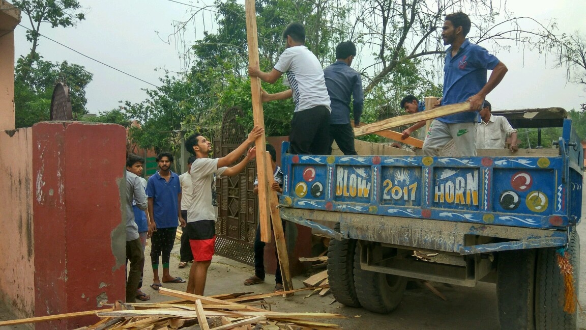 Several people stand on and around a decorated truck near a building
