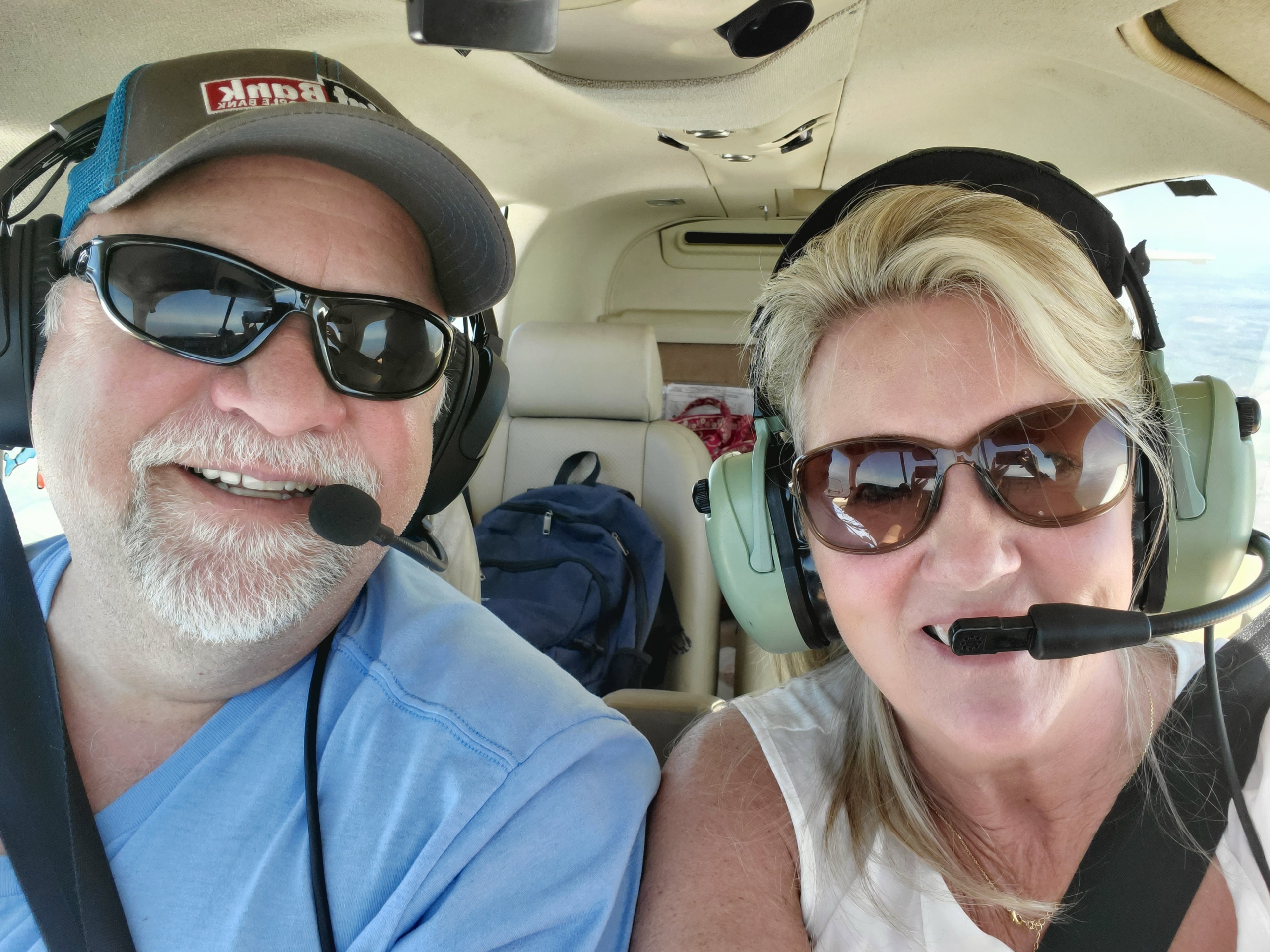 Couple selfie in a small-plane cockpit wearing aviation headsets